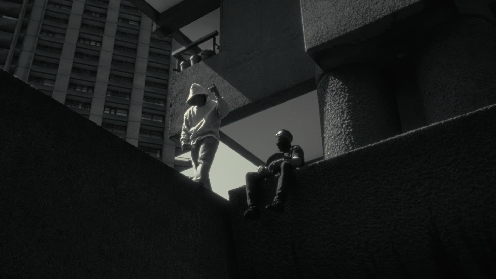 Two brothers among concrete towers and walkways, photographed from below.